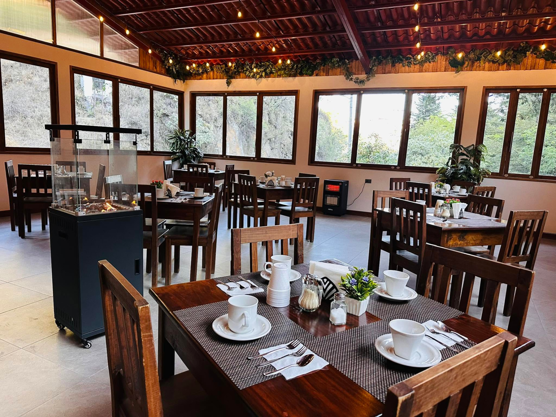 Comedor amplio con mesas de madera, luces cálidas y techos de teja, listo para grupos grandes
