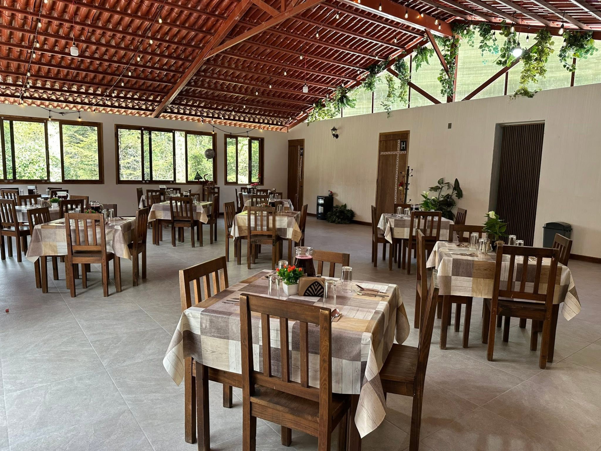 Comedor del restaurante con techos de teja, plantas y mesas listas para recibir
