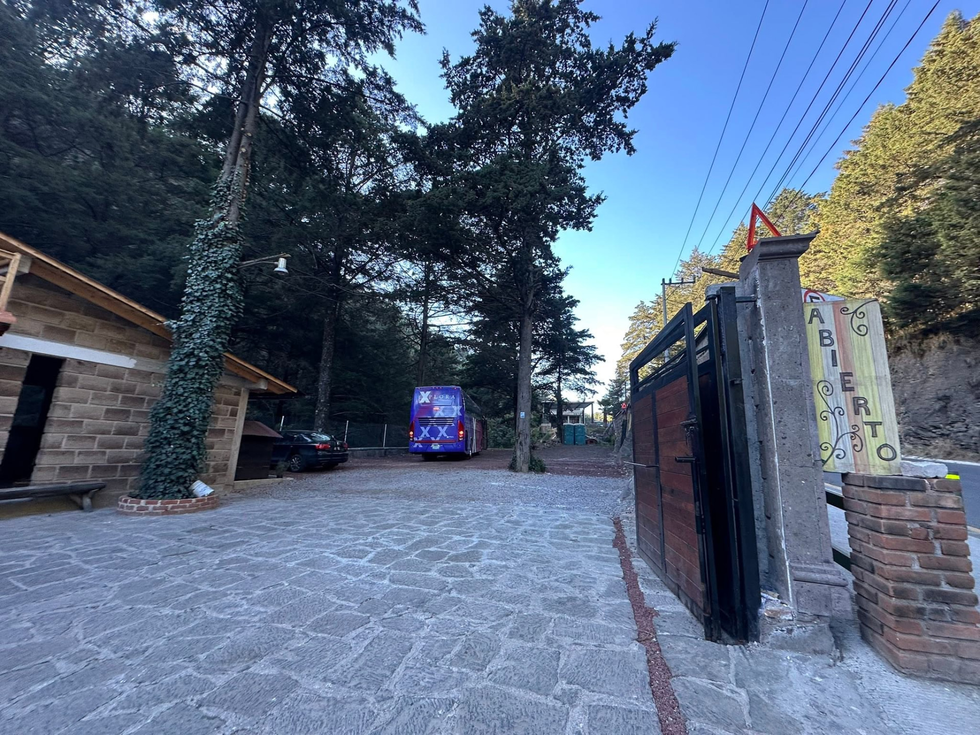 Entrada del restaurante con el portón abierto y un autobús de excursión estacionado